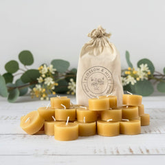 Beeswax candles stacked on a wooden surface with a 'Blossom & Hive' bag in the background.