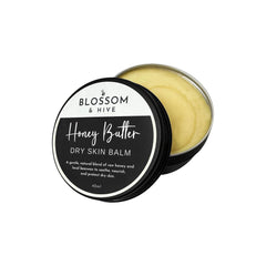 Blossom and Hive Honey Butter Balm in a black tin, lid off showing the creamy yellow balm inside, on a white background