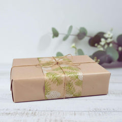 Blossom and Hive gift box wrapped in brown paper with greenery design on a light background