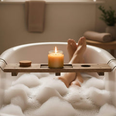 Person relaxing in a bubble bath with a Blossom & Hive Beeswax 12-hour candle on a wooden tray