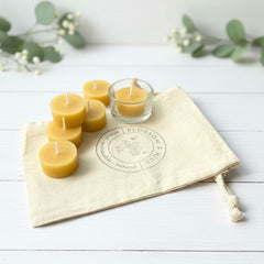 Beeswax candles on a cloth with 'Blossom & Hive' branding on a white wooden surface.