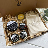 Gift box containing Honey Butter Balm, Honey Lip Care Trio, six beeswax tealight candles with a glass tealight cup, packaged in a kraft box with paper shred and a Blossom & Hive cotton bag.