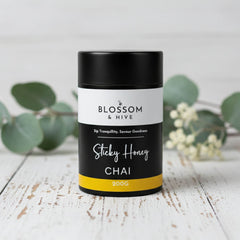 Blossom & Hive Sticky Honey Chai packaging on a wooden surface with greenery in the background