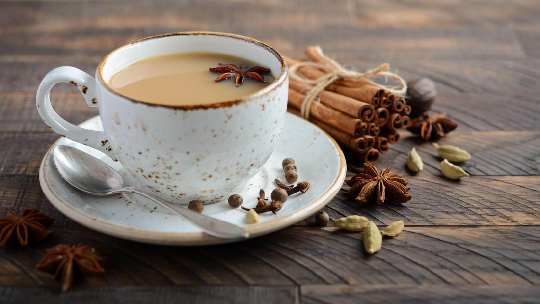 A white china cup filled with chai with cinnamon and other spices on a wooden surface