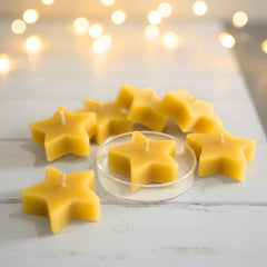 Blossom and Hive star-shaped beeswax candles on a wooden surface with blurred lights in the background