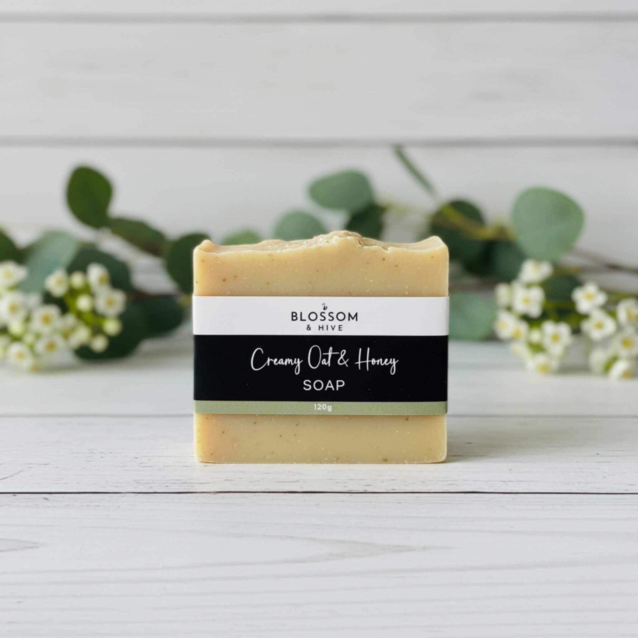 Bar of Honey and Oatmeal soap on a wooden surface with greenery in the background
