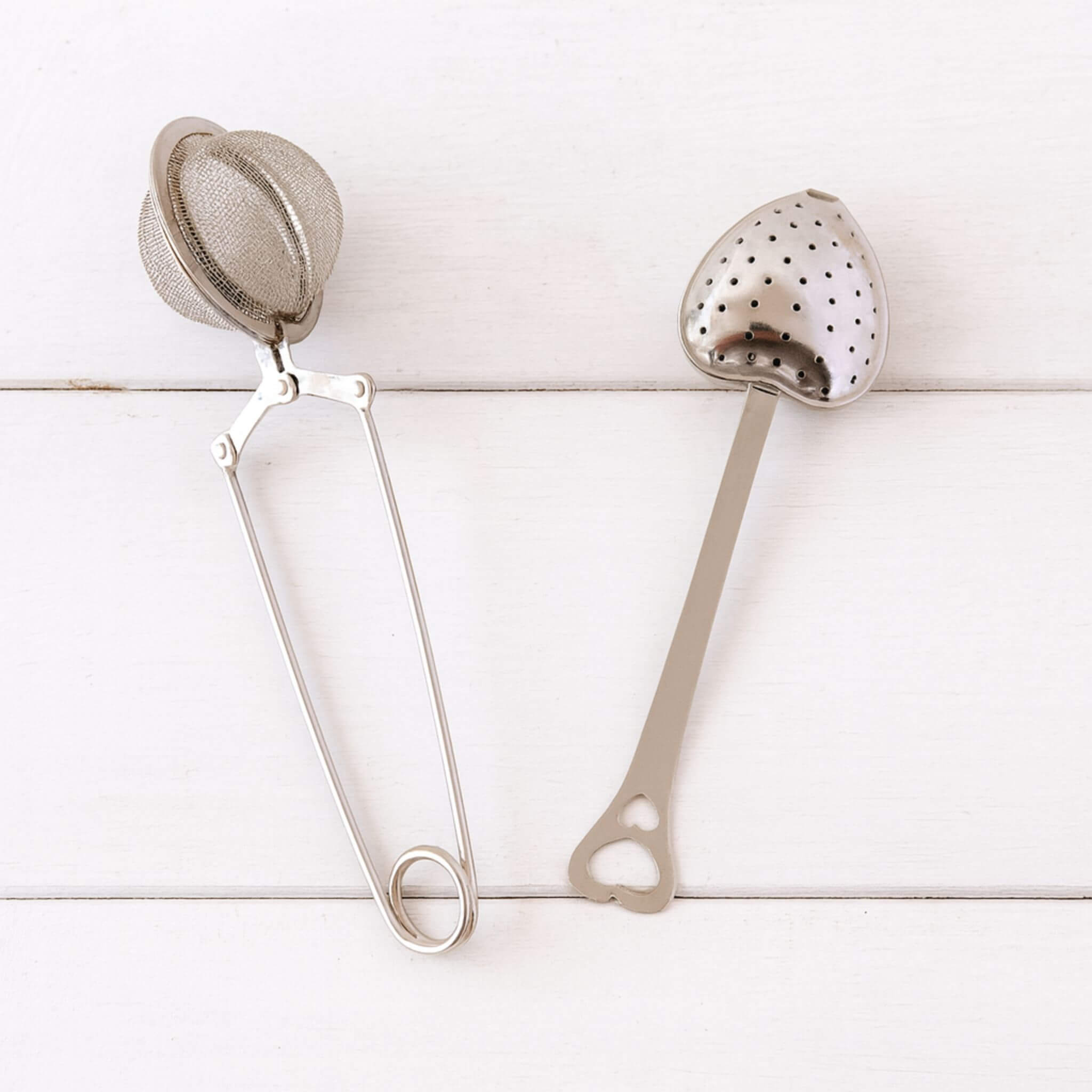 Blossom & Hive Stainless steel mesh tea ball and a heart shaped tea strainer
 on a white timber background