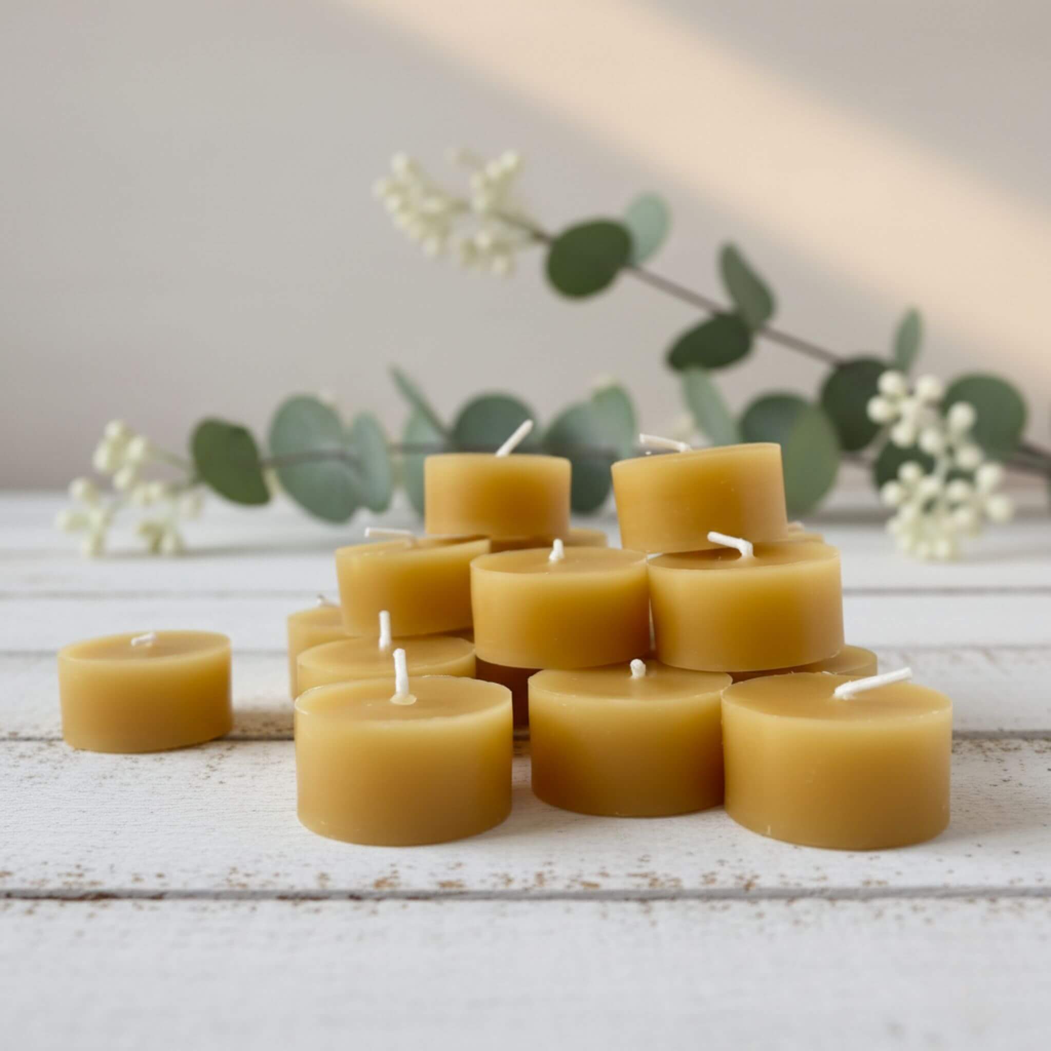 Blossom and Hive pure Australian 
beeswax candles stacked on a wooden surface with greenery in the background