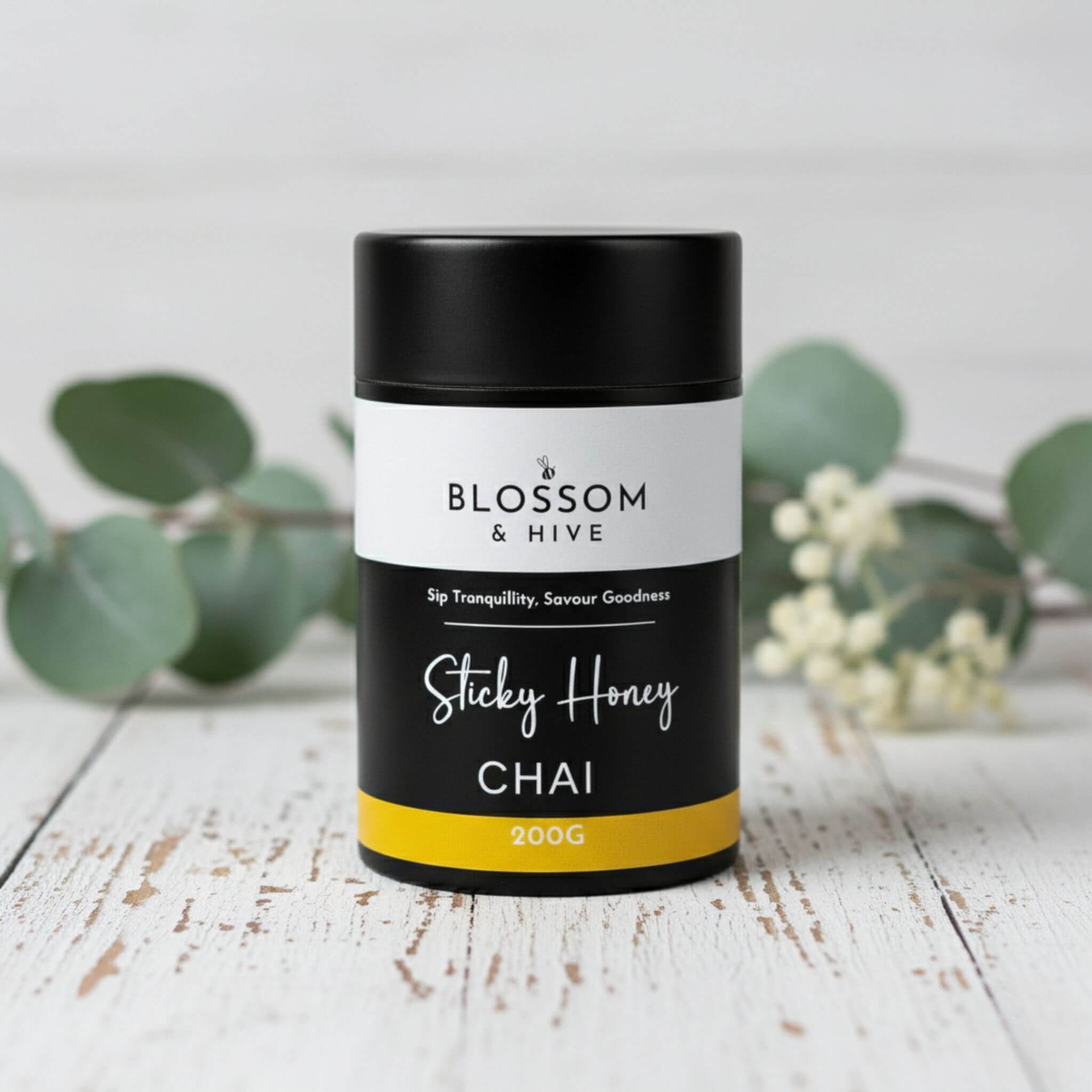 Blossom & Hive Sticky Honey Chai packaging on a wooden surface with greenery in the background