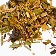 A close-up of Collombatti Naturals Organic Ginger Lift Herbal Tea, showcasing a vibrant blend of dried lemongrass, ginger pieces, hibiscus petals, and calendula. The loose-leaf tea is displayed against a white background, highlighting its fresh, aromatic ingredients and zesty, invigorating character.